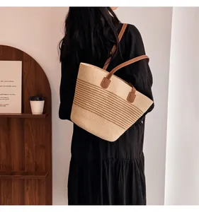 Side view of a striped woven straw tote bag with brown leather handles in a cozy setting