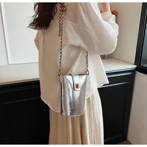 Détail d'un mini sac seau argenté avec bandoulière chaîne et boule dorée