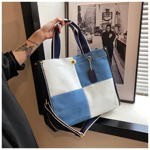 Détail du sac cabas en denim contrasté avec toile bleu-blanc et rivets dorés