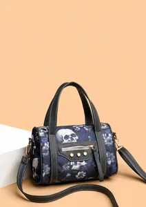 Close-up of skull and blue floral print on a textured Boston bag with metallic rivets