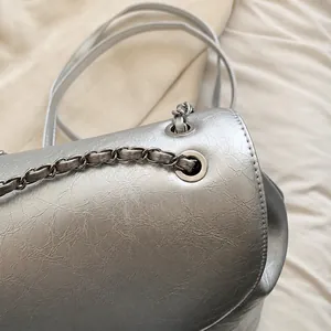 Nahaufnahme der Silberkette durch die Metallöse an der Tasche aus Leder mit Knitteroptik