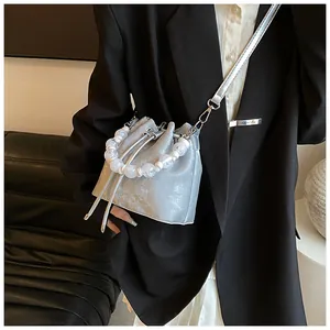 Silver crackle bucket bag with beaded handle worn cross-body over a black suit