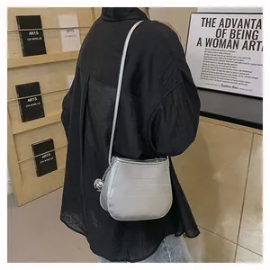 Sac seau métallisé argenté avec pendentif boule porté par un mannequin en ville