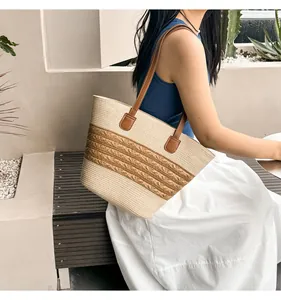 Detail of hand-woven straw tote bag with brown wavy accents and leather shoulder straps