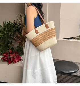 Detail of woven straw tote bag with brown leather straps and striped texture accents