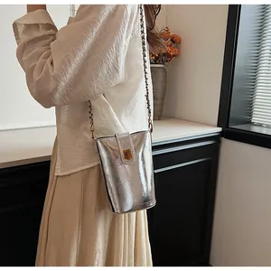 Sac seau argenté métallisé avec bandoulière chaîne porté par un mannequin pour le style