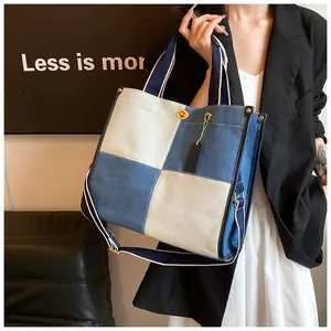 Détail d'un grand sac cabas en denim bicolore avec fermoir en métal et bandoulière amovible