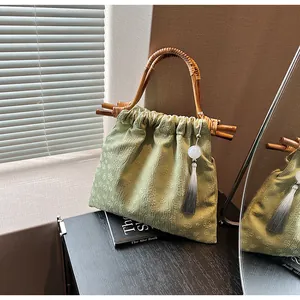 Detail van lichtgroene handtas van reliëfstof met bamboe handvat en elegante zijden kwast