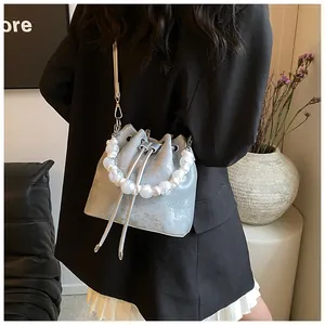 Close-up of silver drawstring bucket bag featuring a large pearl bead top handle
