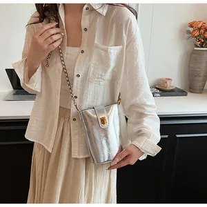 Gros plan du sac seau argenté brillant avec boucle dorée et bandoulière en chaîne