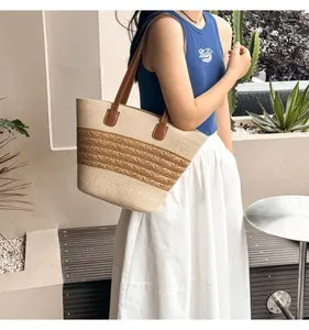 Detailed close-up of woven straw tote bag with bicolor stripes and brown leather straps