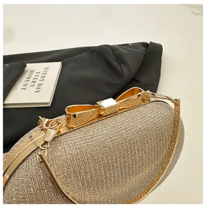 Close-up of champagne gold evening bag with glitter texture and metal bow clasp