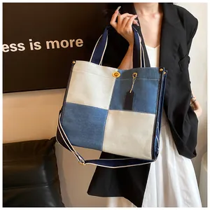 Détail d'un sac cabas en denim bicolore avec fermoir rotatif doré et large bandoulière