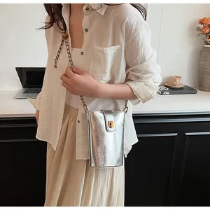Gros plan d'un mini sac seau argenté métallisé avec bandoulière chaîne dorée sur un bureau