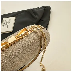 Detail of glitter evening clutch featuring a metal bow clasp and gold chain strap