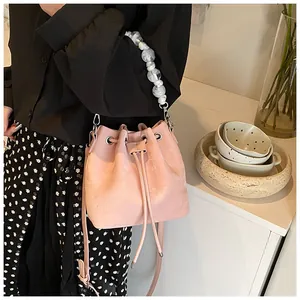 Detail view of pink drawstring bucket bag with white marble bead handle and long strap