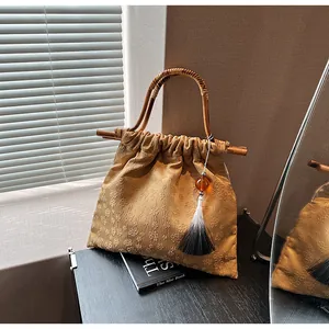 Detailopname van gele jacquard tas met bamboe handvat en zijdezachte kwastjes hanger
