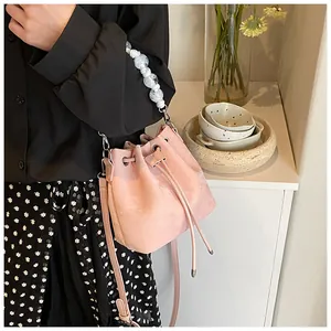 Pink drawstring bucket bag with marble beads handle shown on model in cozy home setting