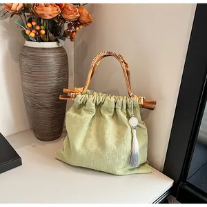 Gedetailleerde close-up van groene jacquard tas met bamboe handvat en zijden kwastje