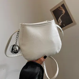 Sac seau minimaliste beige texturé avec pendentif boule argentée et bandoulière longue