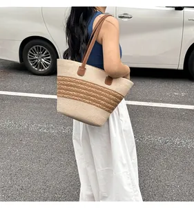 Detail of hand-woven straw tote with brown wave patterns and leather shoulder straps