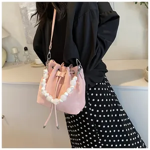 Detail of pink bucket bag featuring large white beaded handle and drawstring closure