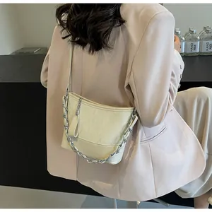 Detail van beige bucket bag met geplooide lederen textuur en zilveren ketting