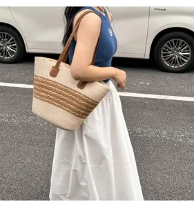 Detail of a large straw tote bag with brown leather shoulder straps for summer travel