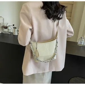 Detailweergave van een beige geplooide emmertas met een stijlvolle zilveren metalen ketting