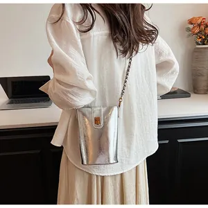Détail du petit sac seau argenté avec fermoir doré et bandoulière chaîne au style chic