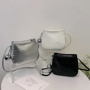 Trois mini sacs seaux en cuir texturé en argent, blanc et noir avec des breloques métalliques