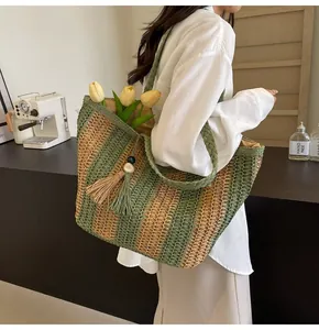 Dettaglio della borsa tote in paglia a righe verdi con nappa di perline e grande capacità