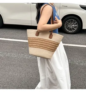 Detail of the straw tote bag showing beige woven texture and brown leather handles
