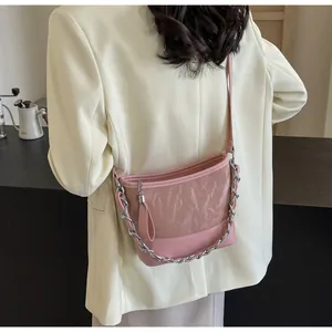Detail van roze emmertas met leer en mesh stiksels en zilveren metalen kettingriem
