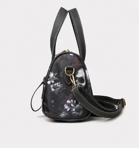 Side view of dark gray crossbody bag with skull and floral patterns and golden hardware