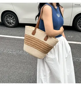Detail of handwoven straw tote bag with striped pattern and premium brown leather handles