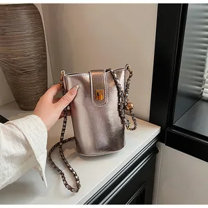 Détail du sac seau métallisé avec bandoulière chaîne dorée et décor boule en métal
