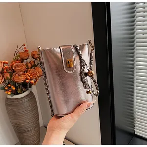 Détail du sac seau argent champagne avec fermoir doré et bandoulière chaîne