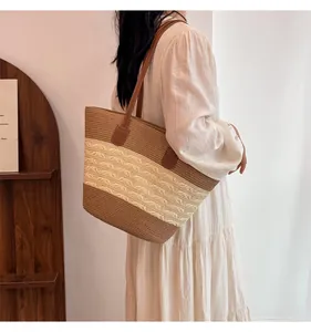 Detail of handwoven straw tote bag with brown leather straps and cutout crochet design