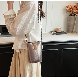 Détail d'un sac seau argenté métallisé avec bandoulière chaîne et boucle dorée