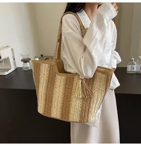 Dettaglio della borsa tote in paglia intrecciata a righe con elegante ciondolo a nappe