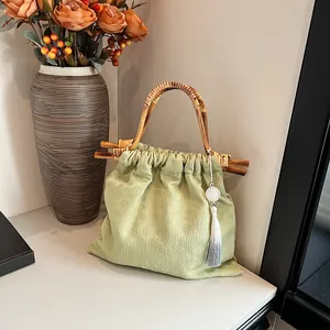Lichtgroene jacquard handtas met bamboe handvat en kwastje in minimalistische stijl