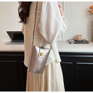 Détail du petit sac argenté miroir à chaîne avec boucle dorée et texture métallique