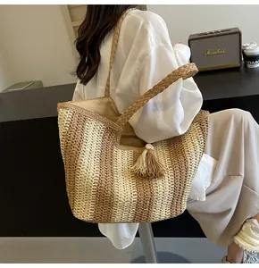 Dettaglio di borsa tote boho in paglia con strisce marroni e tracolle intrecciate