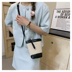 Détail du petit sac seau en toile beige avec des finitions en cuir noir élégantes