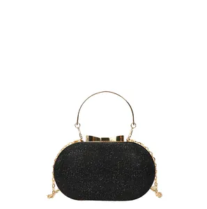 Elegant black sequin clutch bag with golden bow clasp and circular metal handle