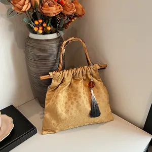 Etnische gouden jacquard draagtas met natuurlijke bamboe handvaten en kwastjesdetail