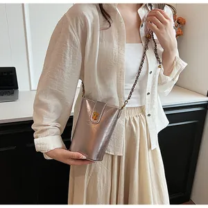 Détail du sac seau vertical argenté champagne avec boucle en T dorée et bandoulière perlée