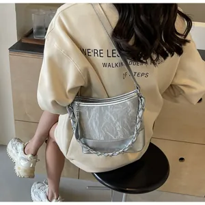 Zilveren emmertas met geplooide metallic textuur en dikke ketting gedragen door model
