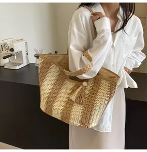 Dettaglio borsa tote estiva in paglia a righe beige con nappe e fodera interna capiente